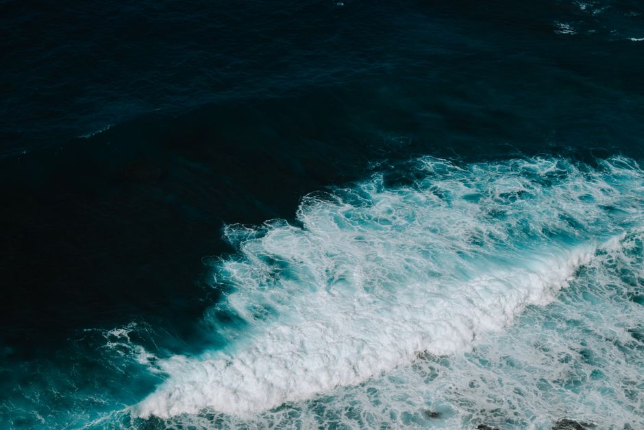 Silueta de barco navegando en mar con olas al atardecer, ambiente épico