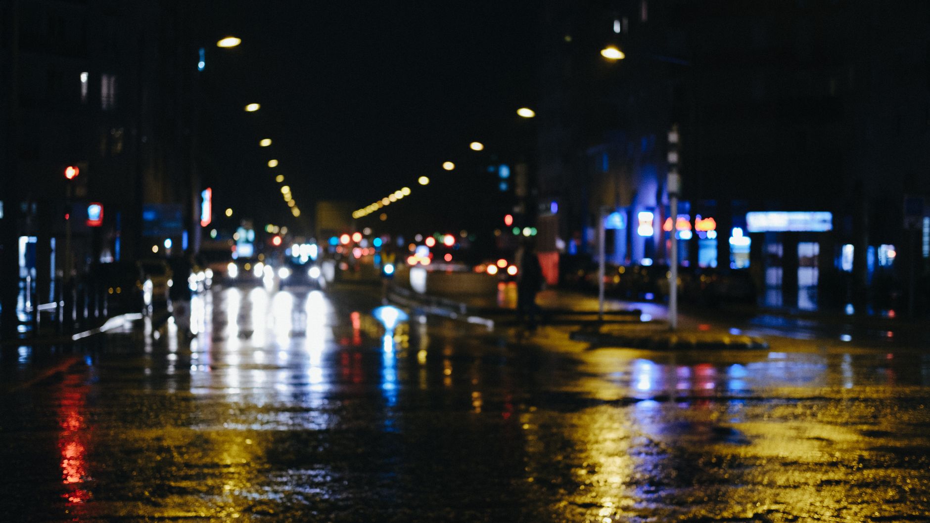 Calle urbana desenfocada de noche con reflejos de luces, imagen ilustrativa del mundo de replicantes de Blade Runner 2099