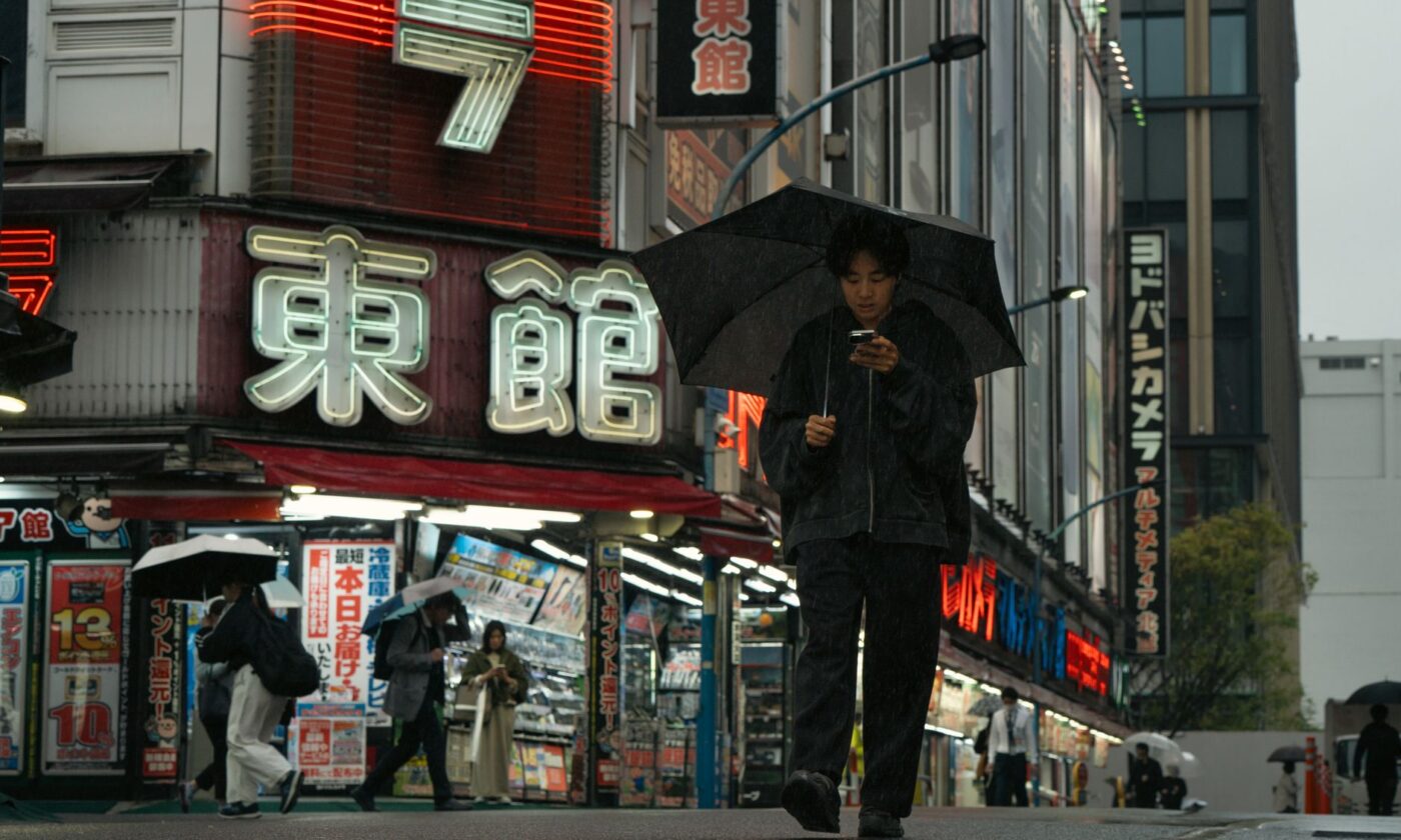 Persona con paraguas camina bajo la lluvia entre luces de neón, imagen ilustrativa de la atmósfera de Blade Runner 2099