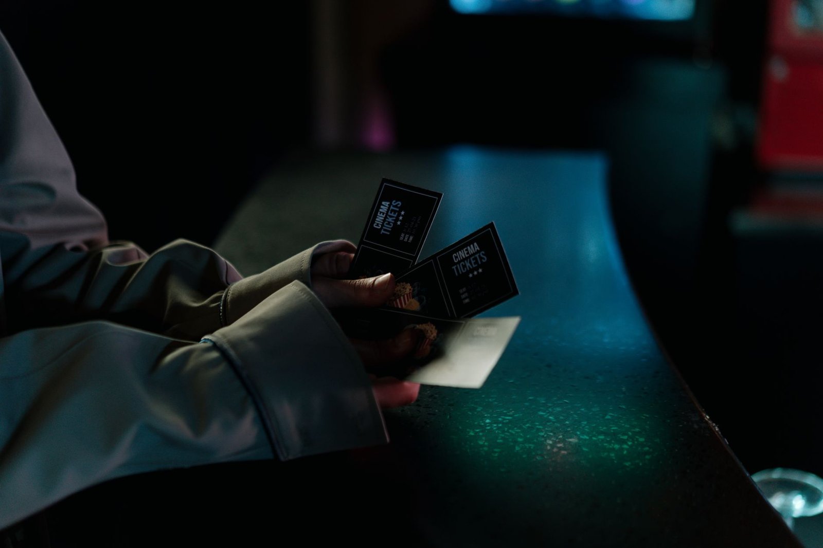 Persona sostiene boletos de cine de noche antes de entrar a una función