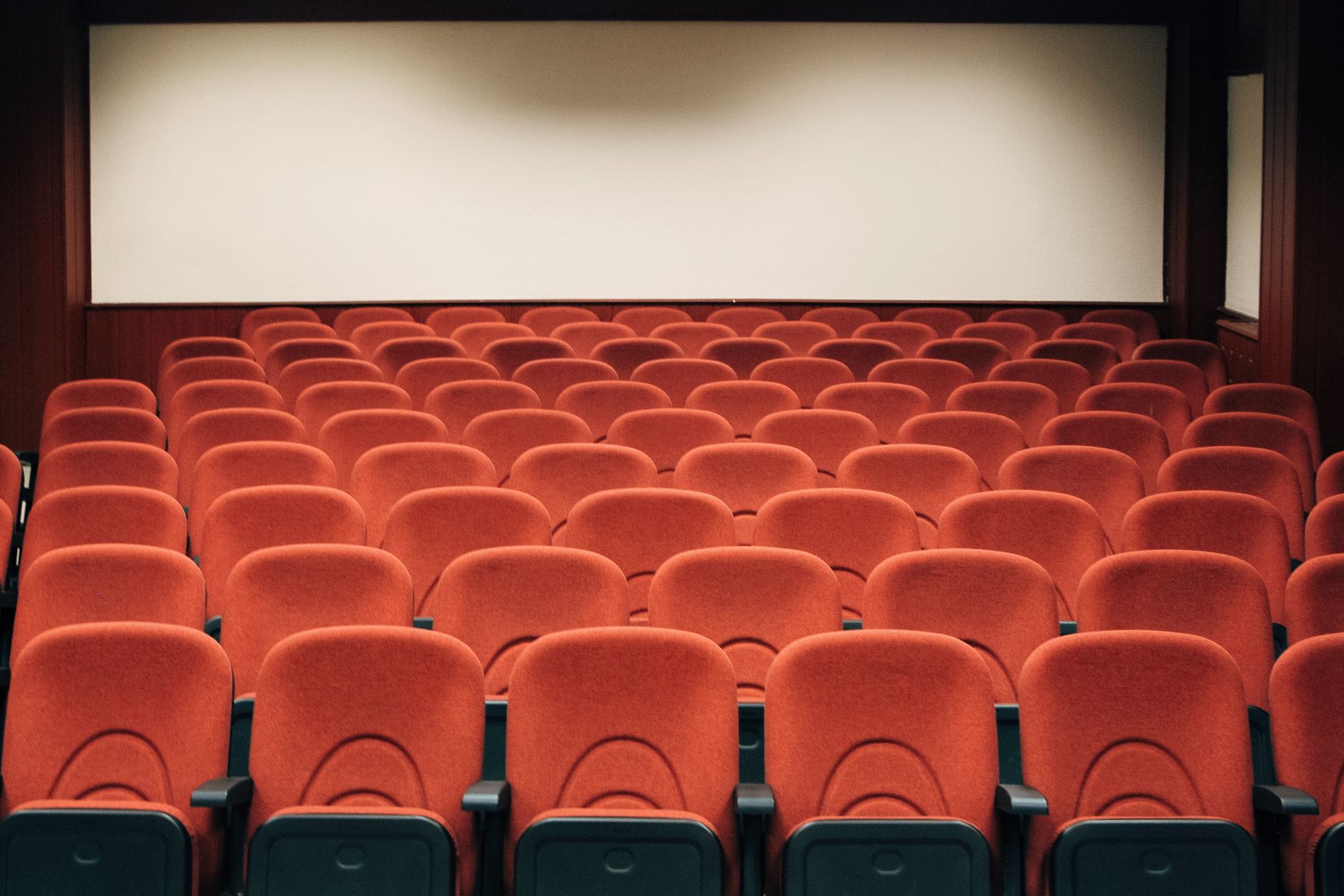 Sala de cine espaciosa con butacas rojas vacías, imagen ilustrativa de una taquilla débil